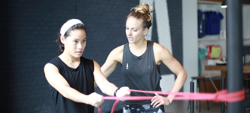 A client doing an exercise with the assistance of a female personal trainer in Bangkok