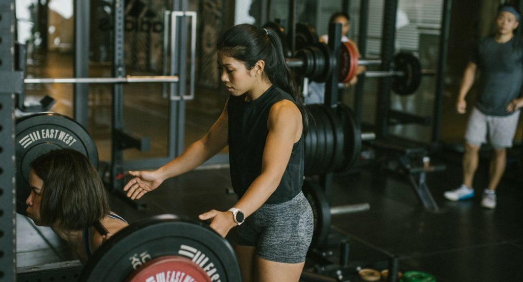 Female personal trainer helping a client with a squat